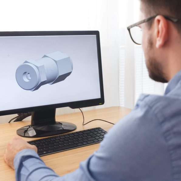 Engineer, Constructor, Designer in Glasses Working on a Personal Computer. He is Creating, Designing a New 3D Model of Mechanical Component in CAD Program. Freelance Work