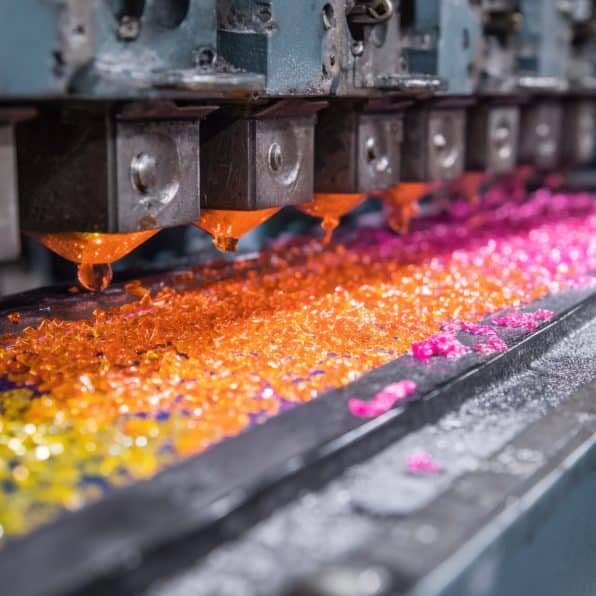 Medium shot of colored vinyl pressing line highlighting vibrant pellets being melted and molded into unique brighthued records.