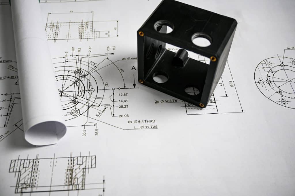 Black plastic prototype lying on technical drawing with measurements, showcasing precision and engineering